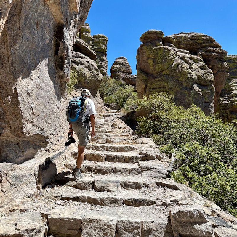 Photo of hiker climbing rocky stairs surrounded by rock towers